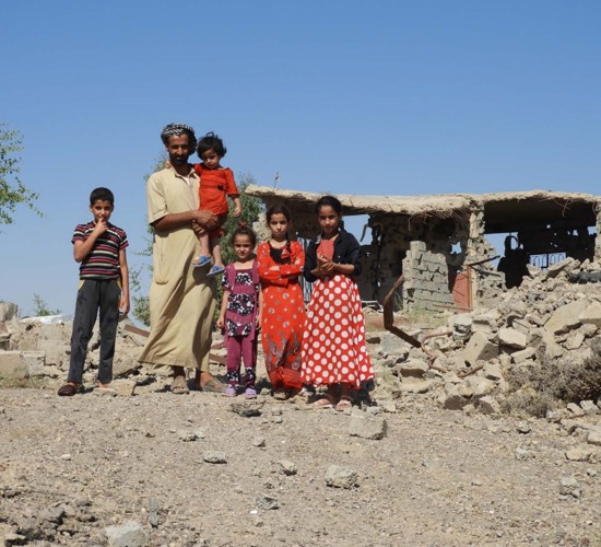 Moshen and his family stand outside their home which has been reduced to rubble