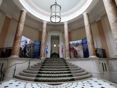 The staircase at Dover House, next to large banners featuring photos of HALO staff in the field
