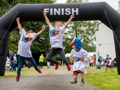 Kids jump in celebration at the finish line as they reach the end of their walk for Syria