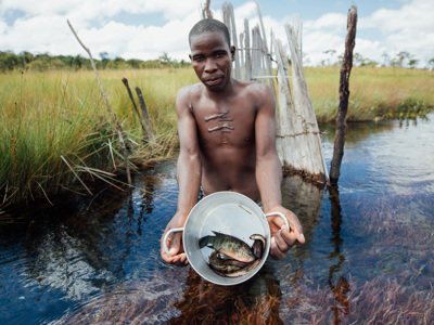 A man holds up a bucket containing fish he has just caught in Angola