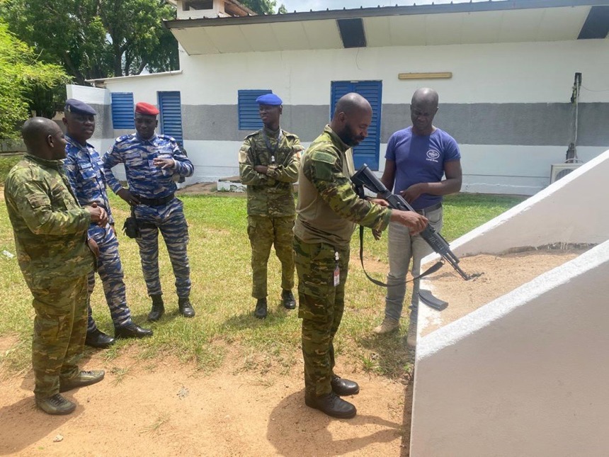Military personnel hold a rifle next to a HALO staff member