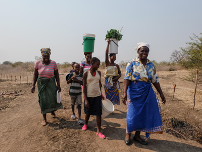 A group of women and children cross the fields next to a minefield in Zimbabwe