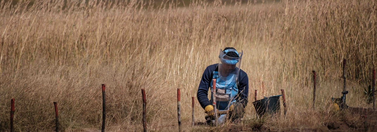 Man in a HALO visor and vest clearing mines in a field in Angola