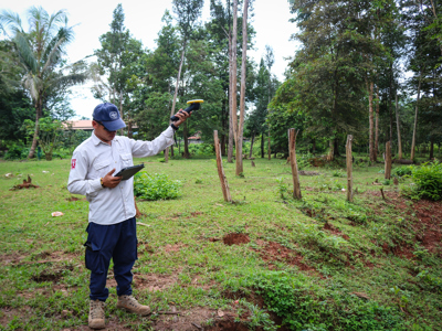 A field data collector in Laos uses a Trimble DA2 GNSS receiver to map survey areas for explosive contamination