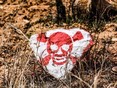 A rock painted with a skull and crossbones lies on the ground near explosive contamination in Syria