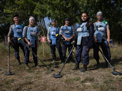 Demining team, in Zolotynka Village, Chernihiv oblast, pose in a minefield with their metal detectors