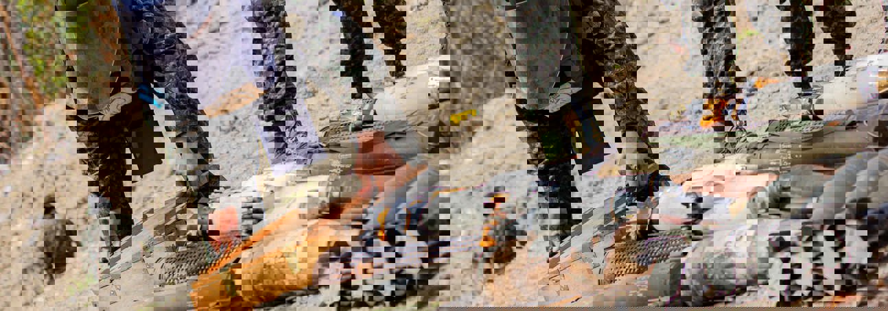 A person in a HALO vest and visor carefully handling a box among a stockpile of weapons in Honduras