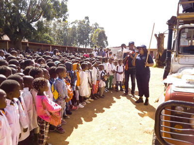 A large group of kids stand in line as they look up to a HALO staff member speaking with a megaphone outside