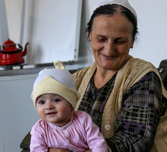 Zejnepe sits in a kitchen with her granddaughter on her lap