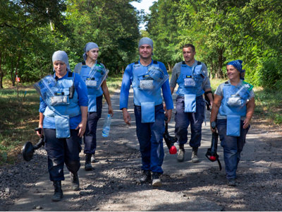 A team of HALO Trust deminers walk down a road in PPE in Ukraine