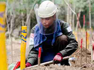 A manual deminer wears PPE and works on marked mines in Cambodia