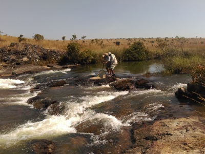 A man stands in the Okavango river holding a small fishing net 